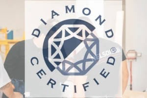 A transparent Diamond Certified logo with a geometric diamond design is overlaid on a blurred image of two people working indoors, one in a black shirt. The background includes shelves and various equipment.
